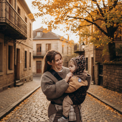 Maman dans une rue avec bebe en echarpe de portage