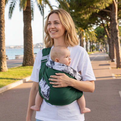 Maman se promène au bord de la mer avec son bébé dans une écharpe de portage - balade verte
