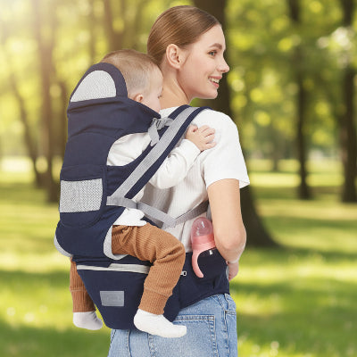 Maman au parc avec bebe au dos en porte bebe ergonomique bleu