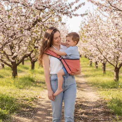 Maman en verger avec enfant en porte bebe evolutif rose