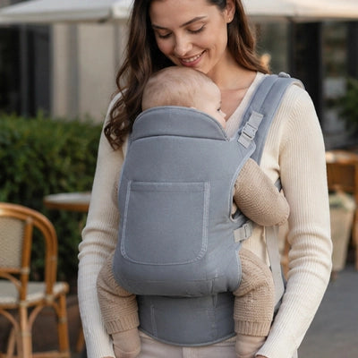 Maman prend une pause sur une terrasse avec son bébé dans un porte-bébé - multifonction gris